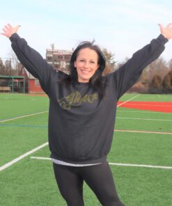 Woman smiling with arms raised on athletic field