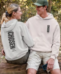 Smiling couple wearing "CHOSEN" hoodies outdoors