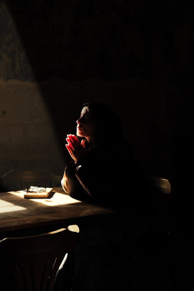 woman praying in dramatic shadowy light