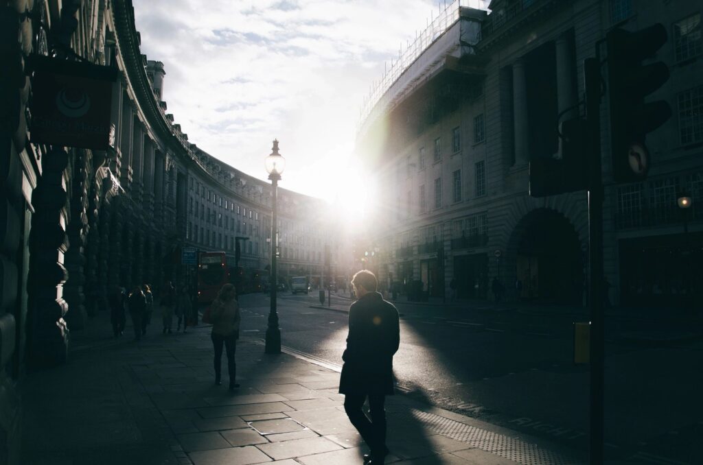 Silhouetted pedestrian on curved city street at sunrise