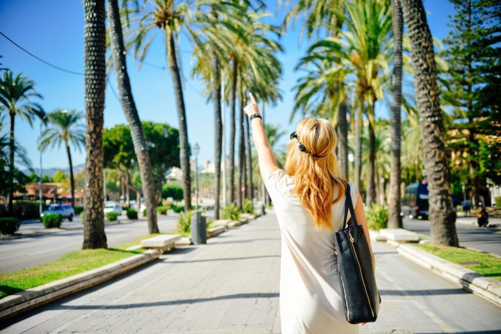 Blonde woman pointing on palm-lined walkway