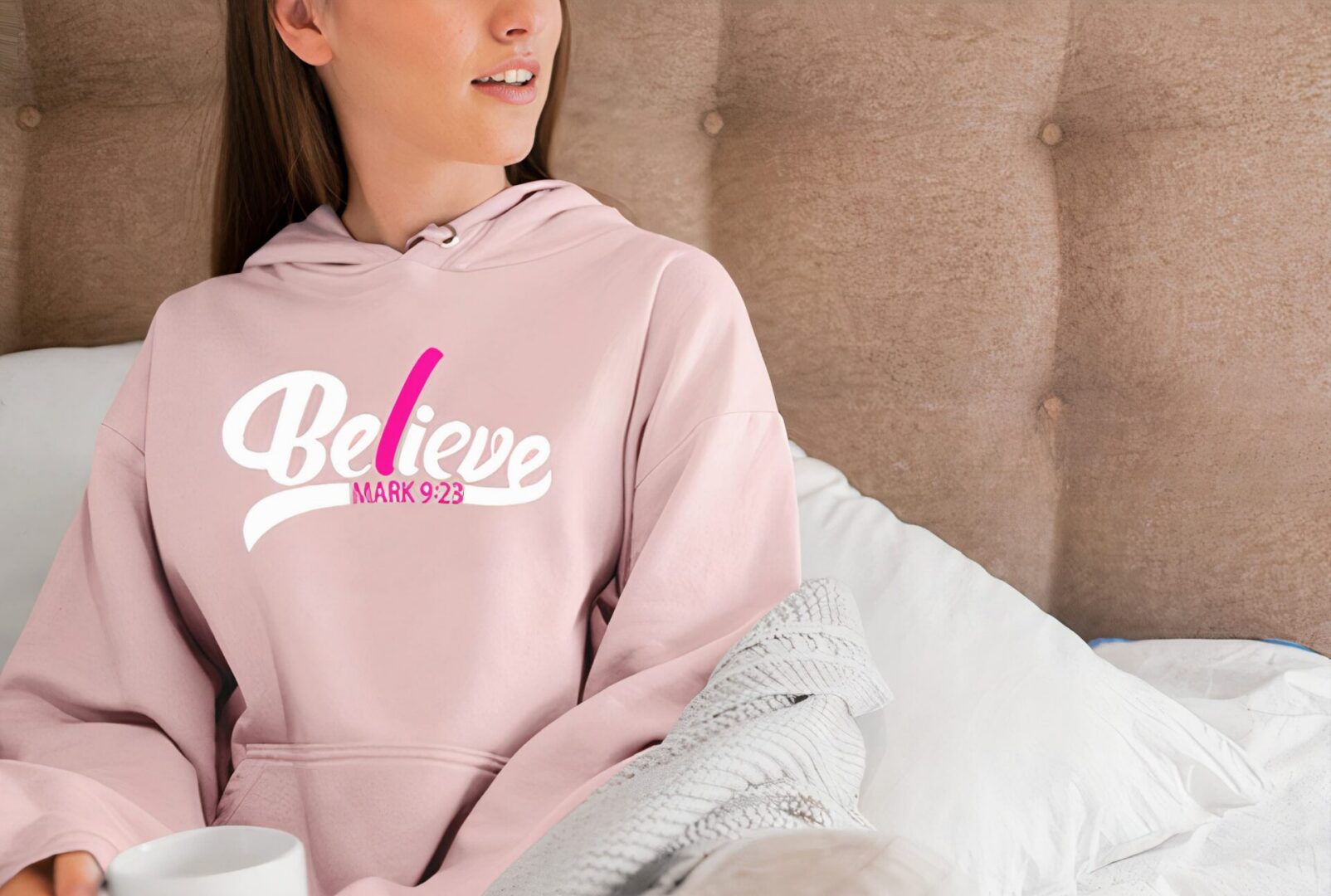 Woman in pink hoodie with "Believe" logo